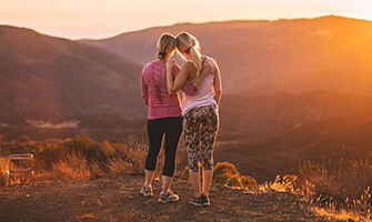 Photo of two women leaning on each other during a hike at sunset for InhouseChemist.vu homepage