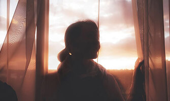 Silhouette of a woman looking outside at sunset on InhouseChemist.vu homepage